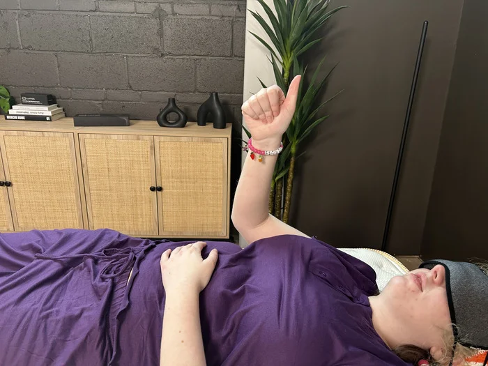 A woman gives the thumbs-up to indicate that she felt movement while testing motion isolation on the Saatva Classic