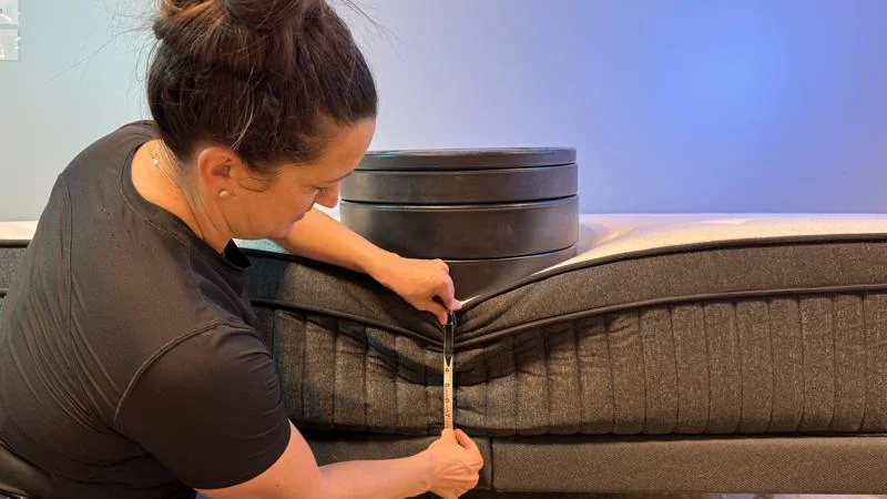 Our tester measures the sinkage from weight plates along the edge of the Titan Plus Luxe Mattress
