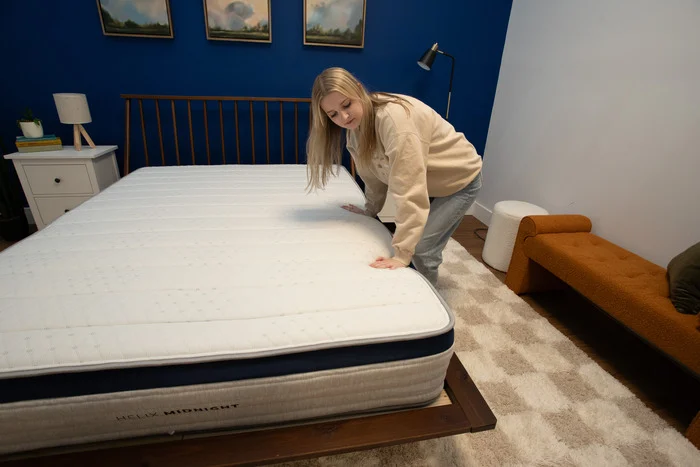 A woman presses into the edge of the Helix Midnight mattress