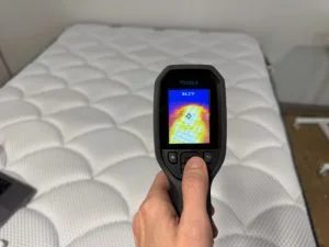 A temperature gun with a reading of 84.2 degrees Fahrenheit pointed at the DreamCloud Premier mattress