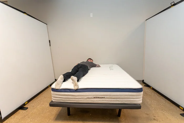A man lies near a glass of water to test motion isolation on the Helix Midnight mattress