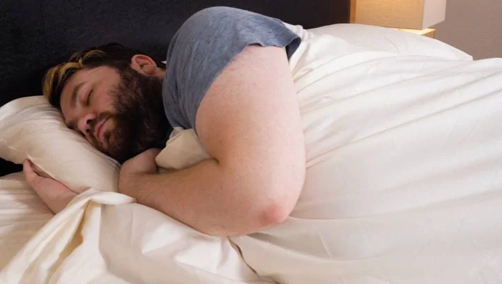 Boll & Branch Percale Hemmed Sheets Side Sleeping A man sleeps on his side with the Boll & Branch Percale Hemmed Sheets.
