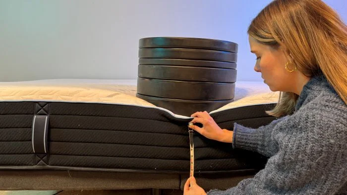 A woman places weights on the Nectar Classic Hybrid mattress to measure sinkage.