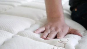 A man presses into the top of a mattress. A man presses into the top of a mattress.