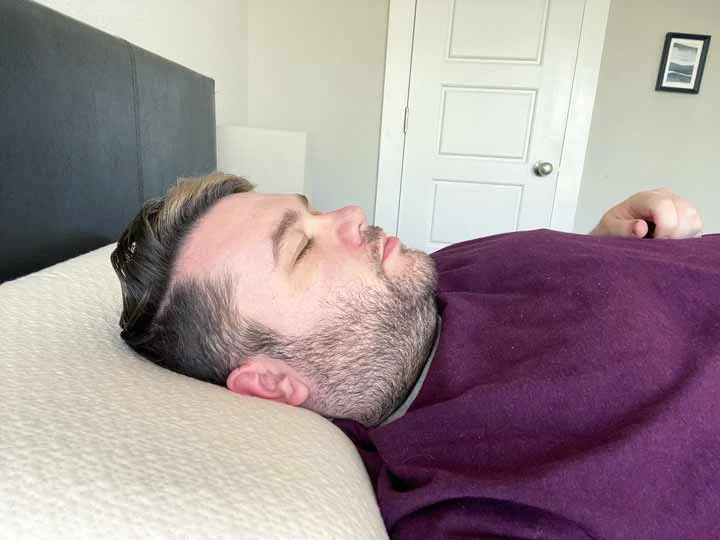 A man sleeps on his back with the Avocado Molded Latex Pillow