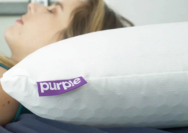 A woman rests on her back using the Purple Harmony pillow. A woman rests on her back using the Purple Harmony pillow.