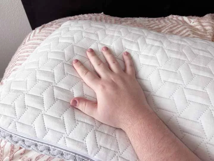 A hand rubs the cover of the Luxome Layr pillow.