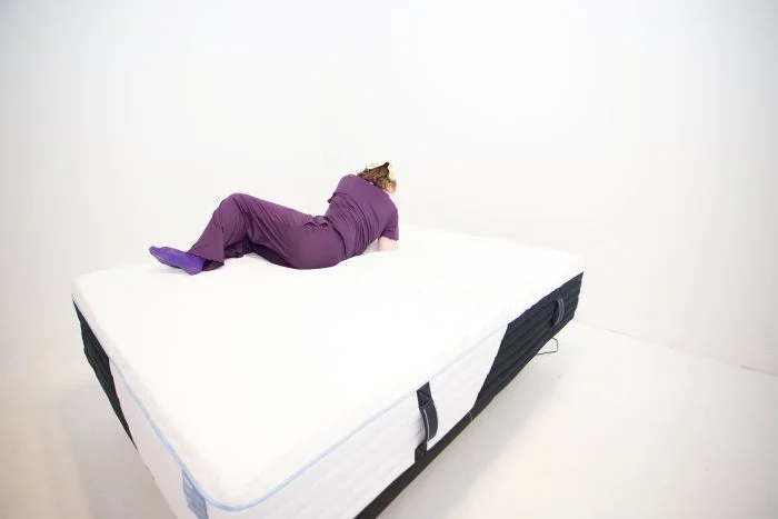 A woman tests motion isolation on the Nectar Classic Hybrid mattress.