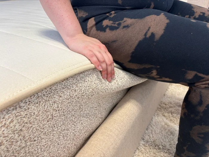 tester seated on the edge of the birch natural mattress to test edge support