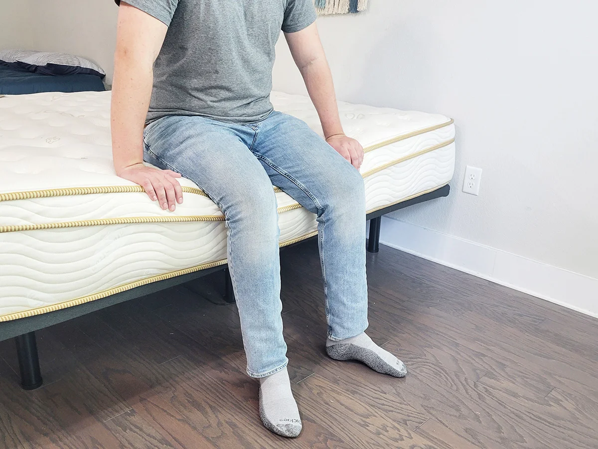 man sitting on the edge of the Saatva Classic mattress