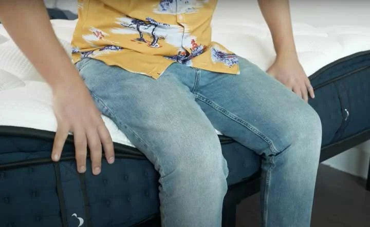 A man rests on the edge of the DreamCloud Premier Rest A man rests on the edge of the DreamCloud Premier Rest