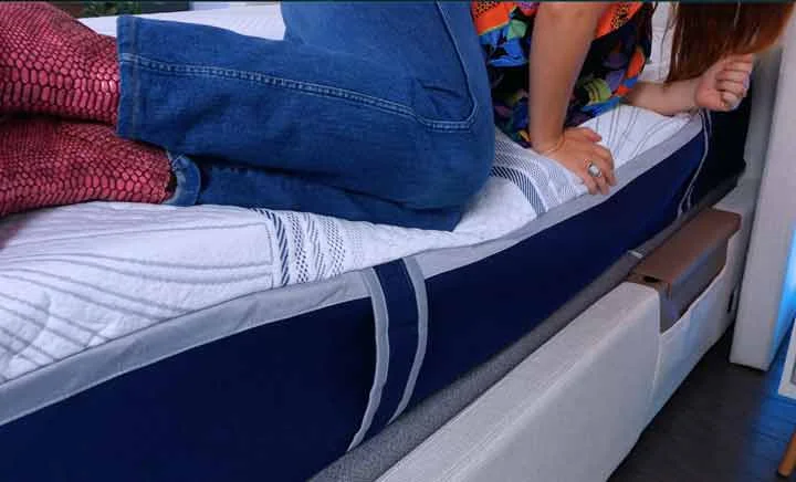 A woman on her side at the edge of the Novaform mattress to test its edge support.