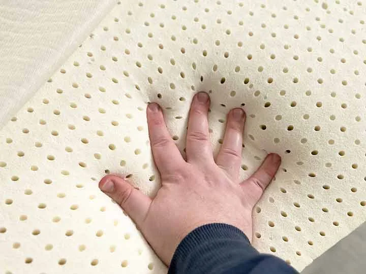 A hand presses into the latex foam of the Brooklyn Bedding Latex Topper