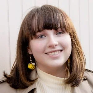 About the Mattress Clarity Team Livvi wearing felted bumblebee earrings and smiling.