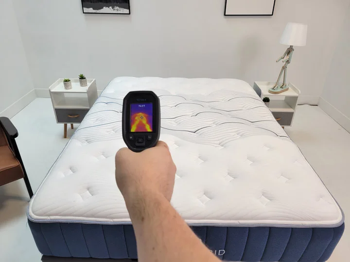 A man measures the temperature of a mattress using a temperature gauge
