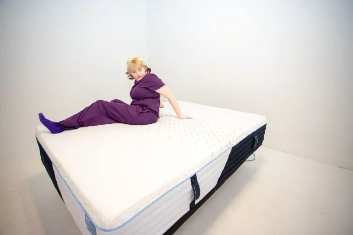 A woman tests motion isolation on the Nectar Classic Hybrid mattress.