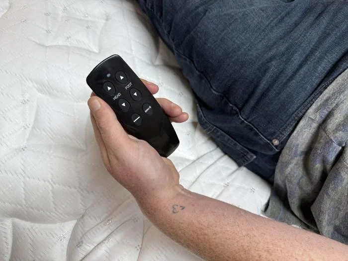 Holding the remote control for a Brooklyn Bedding Ascension Luxe Adjustable Base