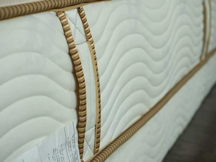 A view of the side of the Saatva Youth mattress with handles and organic fabric.