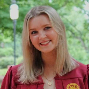 Riley smiling in a red graduation robe.