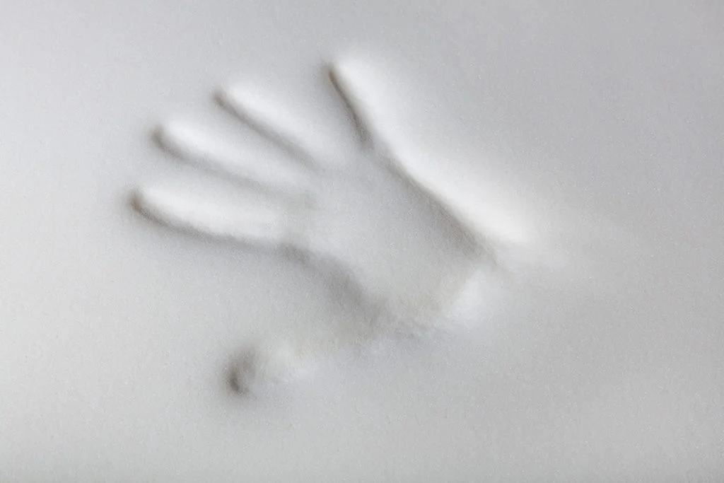 An imprint of a hand in a white piece of memory foam