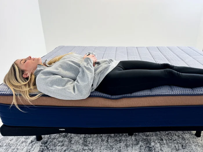 A woman rests on her back at the very edge of the Brooklyn Bedding CopperFlex mattress