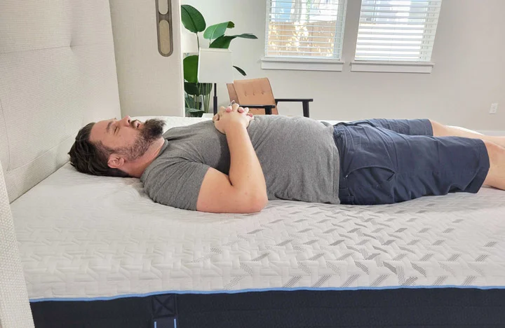 A man sleeps on his back on the Nectar Hybrid