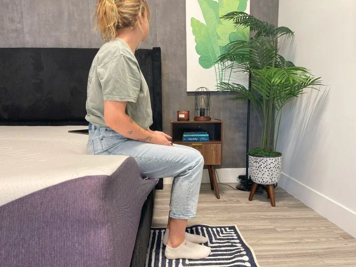 A woman sits on the edge of the Polysleep Luna mattress