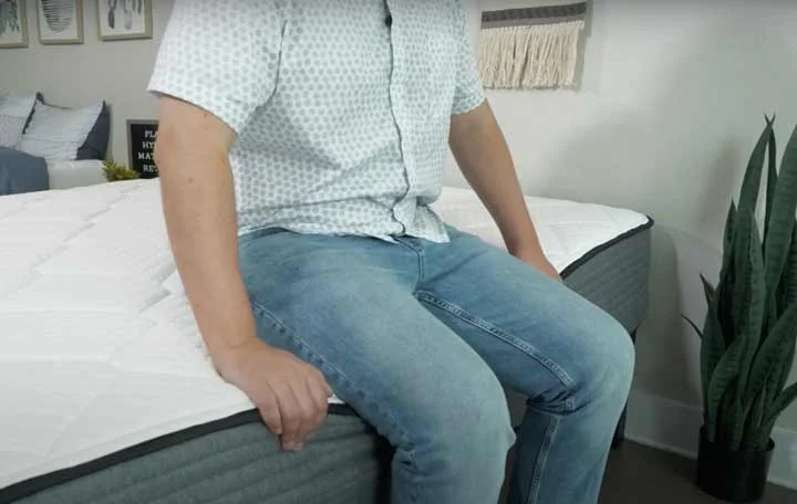 Man sitting on the edge of the plank firm mattress