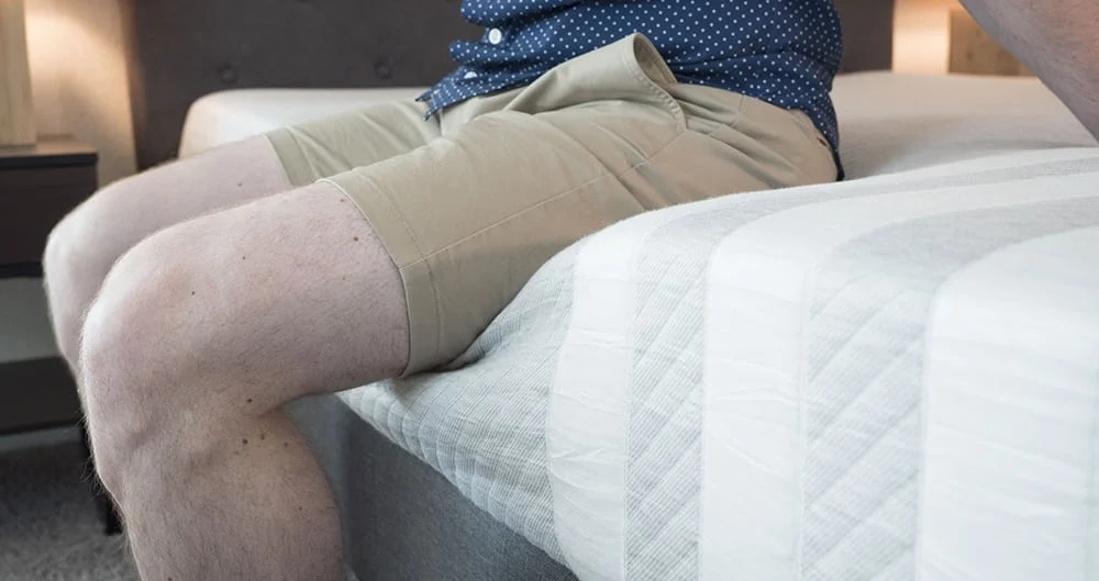 A man sits on a mattress.