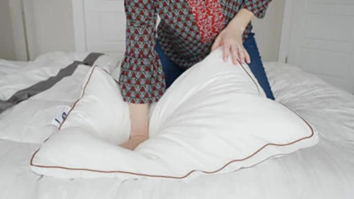 A person leans on a Saatva Latex Pillow to test responsiveness.
