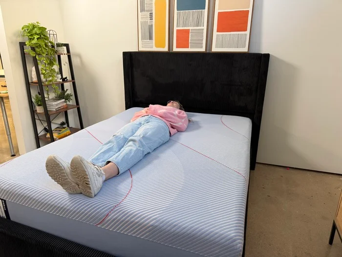 woman in a pink sweater resting on her back on a sealy posturepedic hybrid mattress
