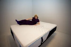 A woman tests motion isolation on the Nectar Classic Hybrid mattress.