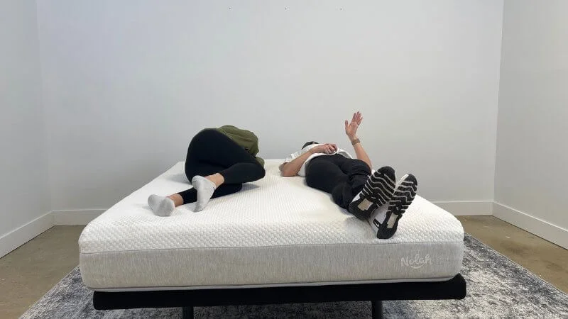 Two testers lying in the Nolah Original mattress to rate and score the mattress's motion isolation capabilities