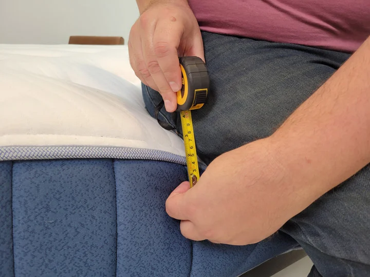 A man measures the edge support of the Bear Elite Hybrid mattress