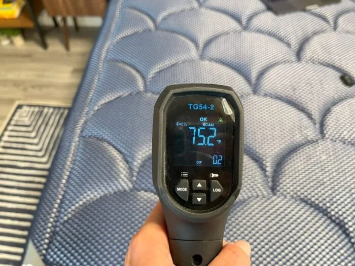 Our tester using a temperature gun to get a reading of the DreamCloud Luxe Memory Foam mattress before laying on it.