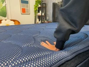 Our tester presses down on the DreamCloud Luxe Memory Foam mattress