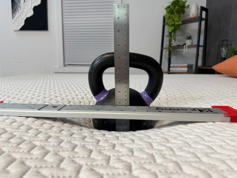 A kettlebell sinking into the surface of the Tuft and Needle Original mattress