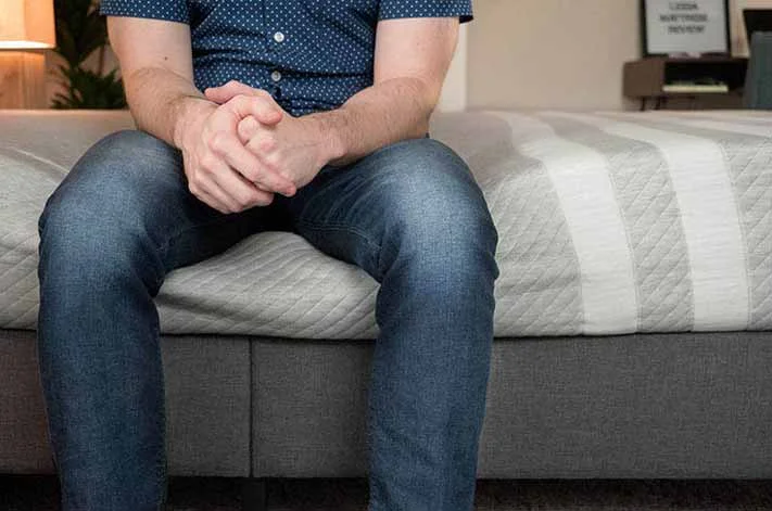 A man sits on a mattress.