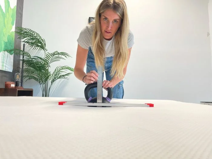A woman measures sinkage with a kettlebell