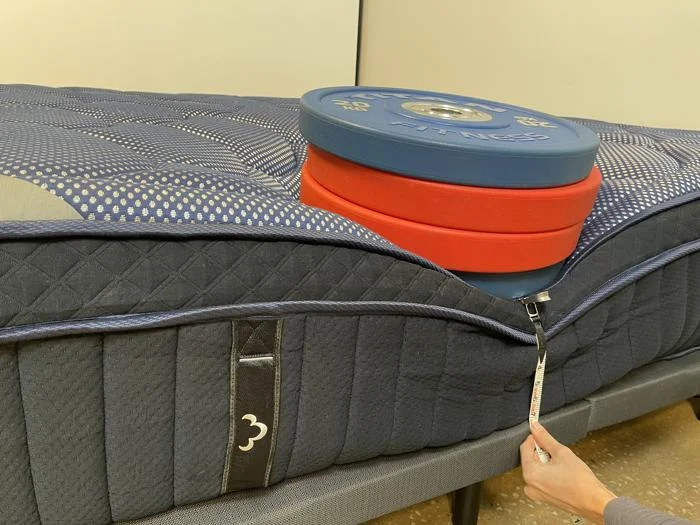 Measuring weight plates on the edge of a DreamCloud Luxe Hybrid