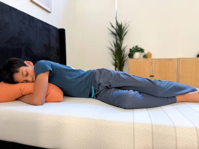 A young tester rests on his side on the Leesa Kids mattress