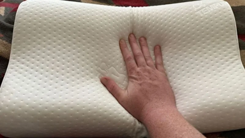 A hand presses down into a pillow.