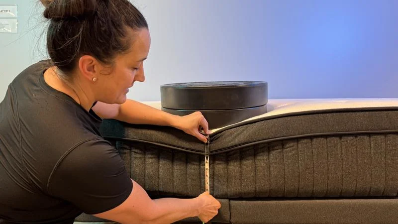 Our tester measures the sinkage from weight plates along the edge of the Titan Plus Luxe Mattress