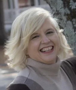 Sosha wearing a turtleneck and smiling.