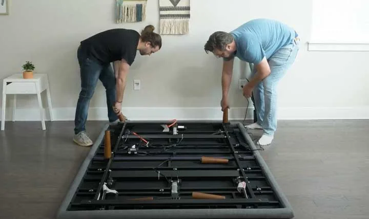 Two men screw the legs onto the Purple Ascent base Two men screw the legs onto the Purple Ascent base