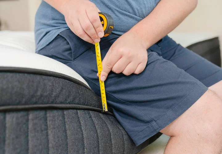 a man sits along the side of the Titan Plus mattress