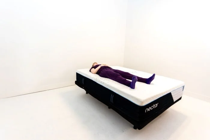 A woman lays on her back on the Nectar Classic Hybrid mattress.