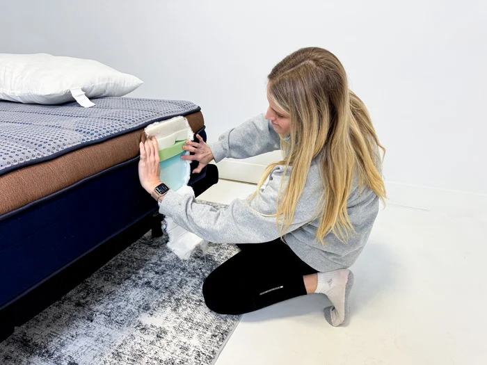 A woman examines the internal foam layers of the Brooklyn Bedding CopperFlex mattress