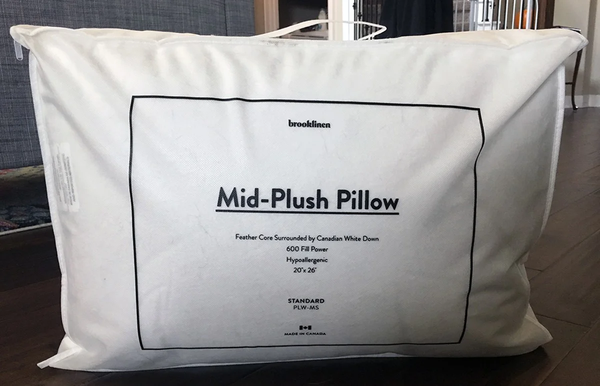 A Brooklinen Mid-Plush Down Pillow sits in its bag. 