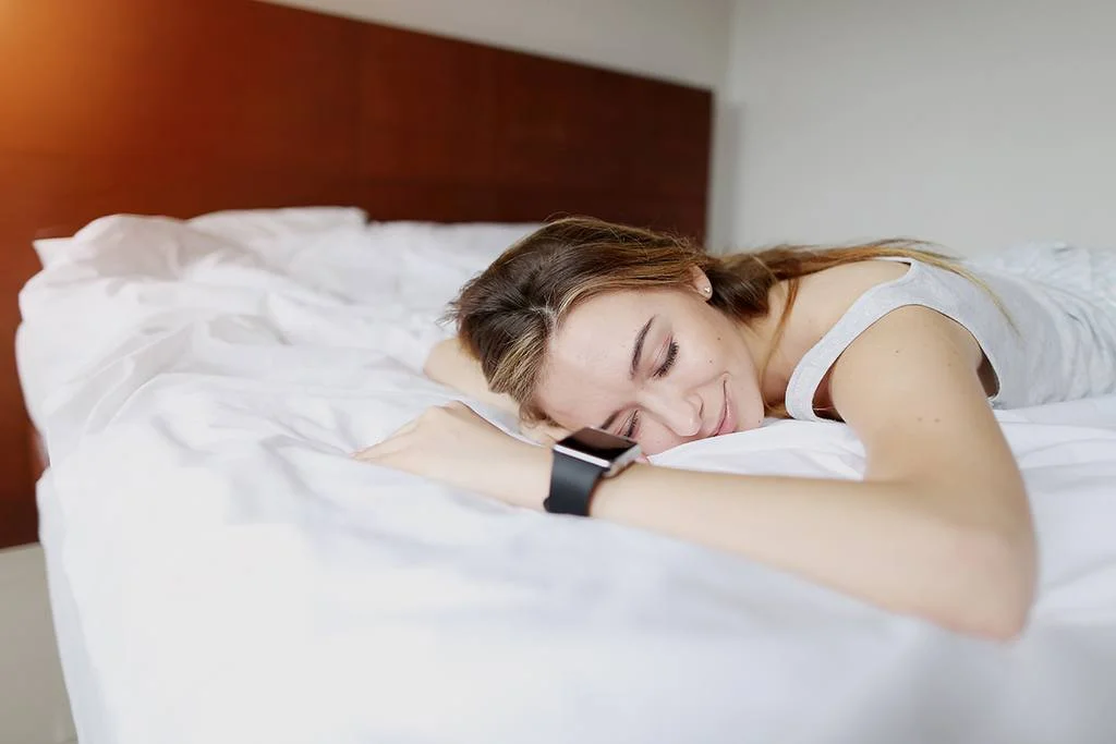 a woman sleeps with a sleep tracker on her wrist